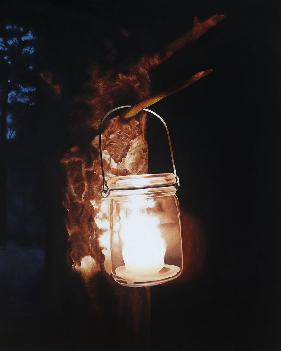 A candle in a jar hanging on a tree branch